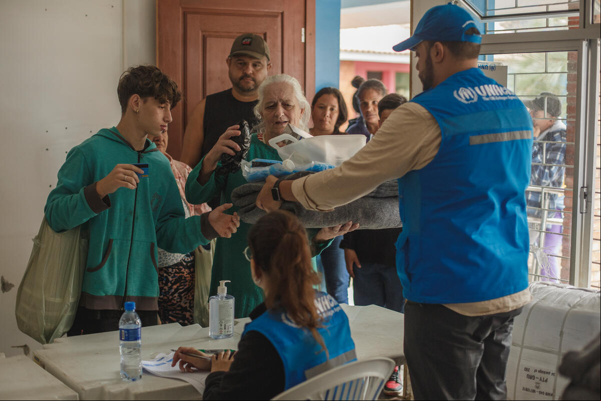Gathered in a simple get-together, refugees living in the Sarandi neighborhood of Porto Alegre, the capital of Rio Grande do Sul, Brazil, interacted with Brazilian families from the same community. The event was a chance to thank the locals for their warm welcome, acknowledge the they received during the floods between late April and early May 2024, and reaffirm their commitment to rebuilding their lives once again.The Brazilian and refugee families attending the event, held at the premises of Aldeias Infantis SOS, a UNHCR partner organization in Porto Alegre, had access to counseling services and were referred for documentation and social assistance according to their needs, with from the Jesuit Service for Migrants and Refugees (SJMR), another UNHCR partner specializing in migration, forced displacement, and refuge. All participants received essential items donated by UNHCR to the Rio Grande do Sul state government, such as mosquito nets, solar lamps, and blankets.Rio Grande do Sul has a Brazil. Flood-affected Brazilians and refugees in Rio Grande do Sul celebrate World Refugee Day