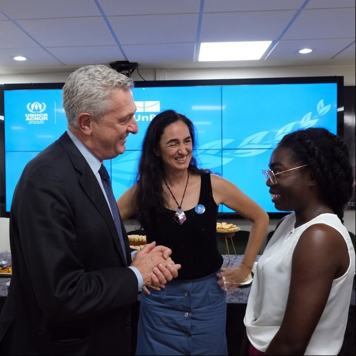 Alto Comissário Filippo Grandi em encontro com as universidades conveniadas à Cátedra Sérgio Vieira de Mello A imagem mostra três pessoas conversando em frente a uma grande tela que exibe o logotipo e o texto do ACNUR (Alto Comissariado das Nações Unidas para Refugiados).