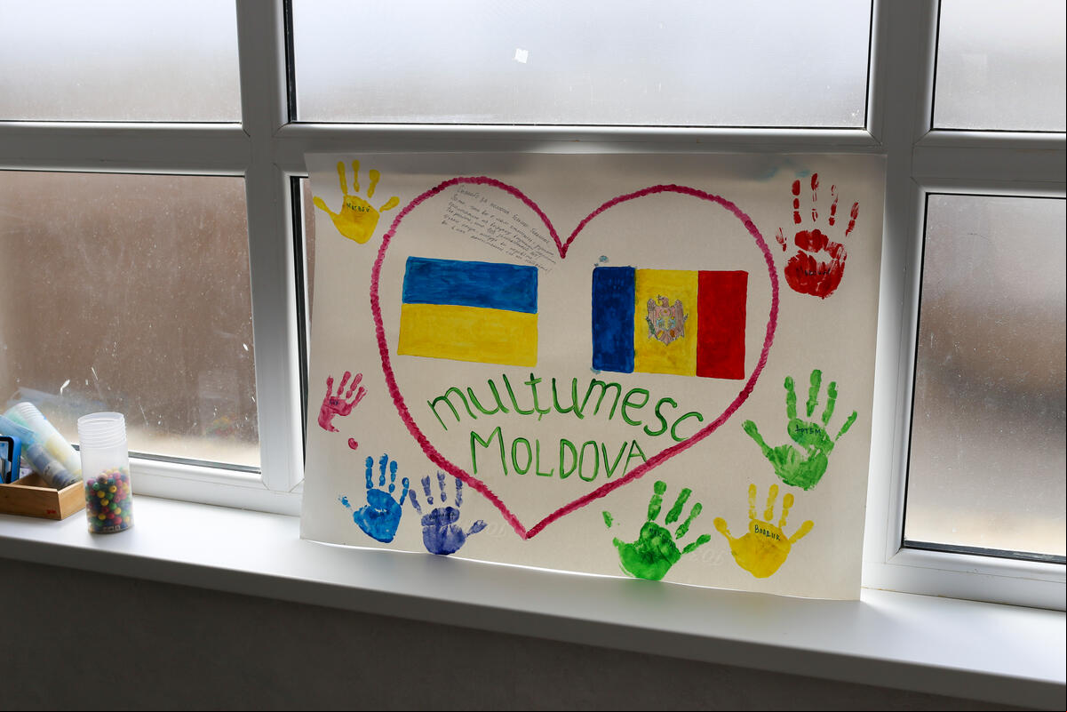 En una ventana hay un dibujo de las banderas de Ucrania y Moldavia rodeadas de un corazón y marcas de manos de un niño