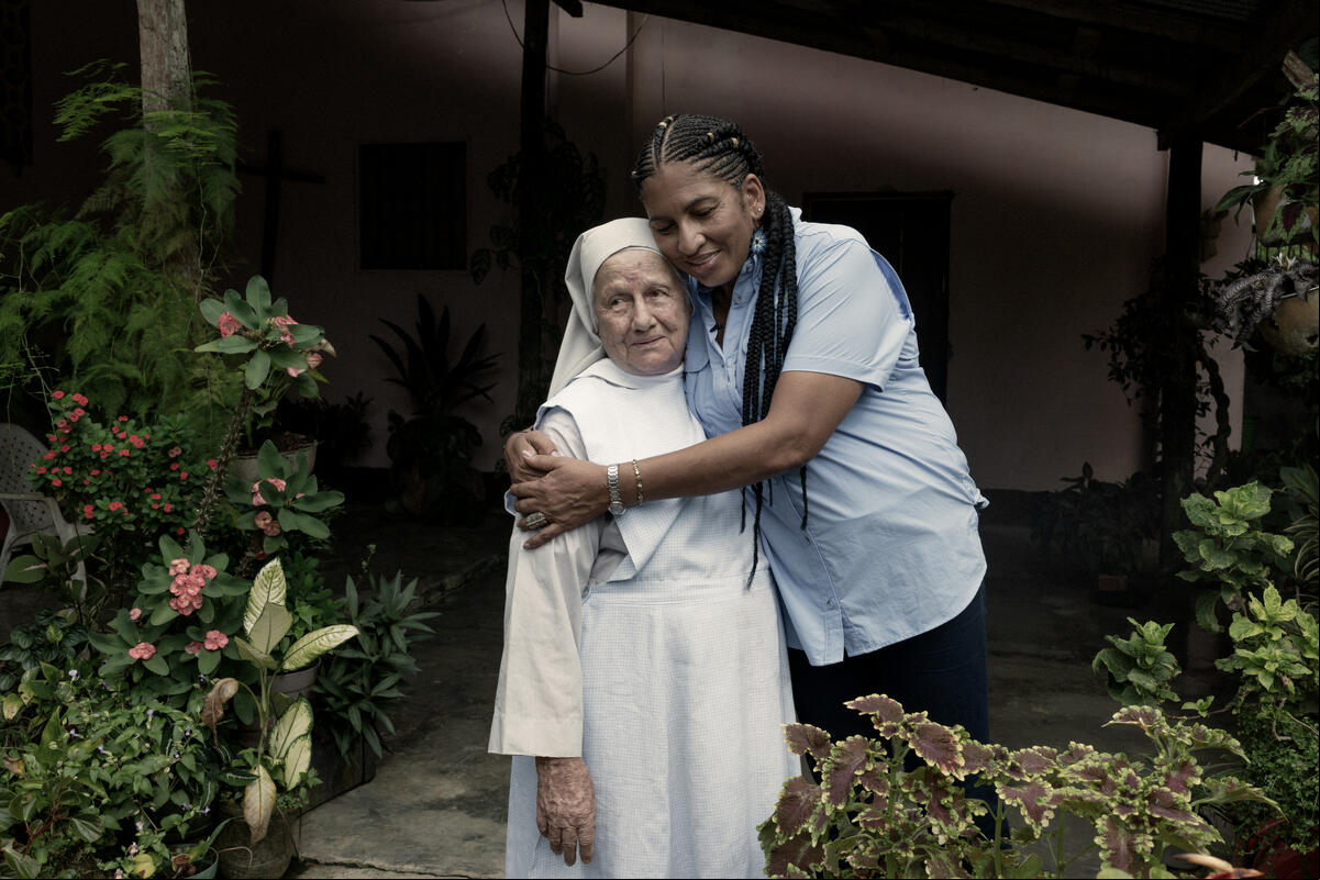Una mujer abraza a una religiosa vestida con hábito blanco.