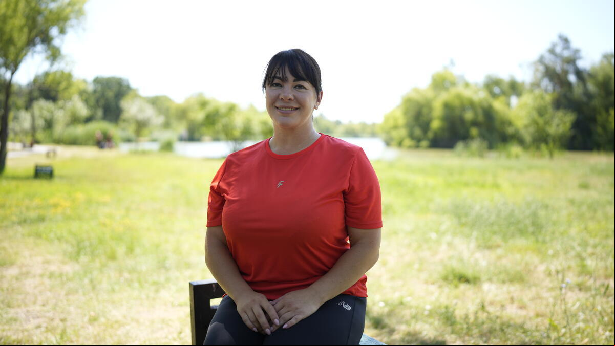 Una mujer sentada en una banca del parque frente a un lago