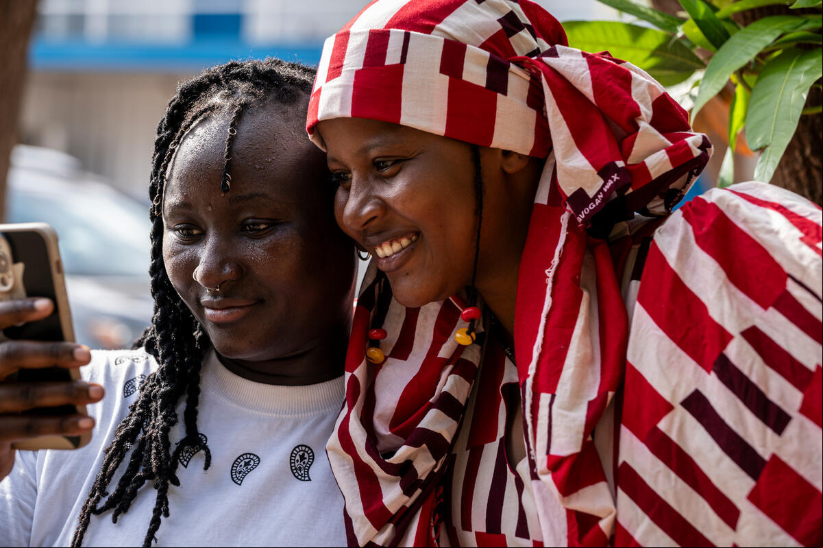 En África, dos mujeres se toman una selfi. Una de ellas lleva puesta una indumentaria a rayas de colores rojo y blanco.