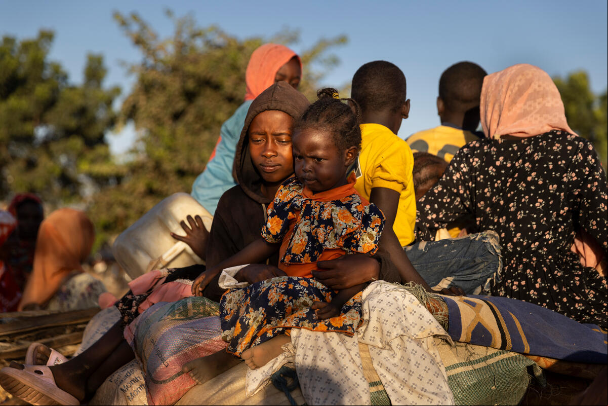 Un grupo de mujeres y niños viajando en parte trasera de una carreta.
