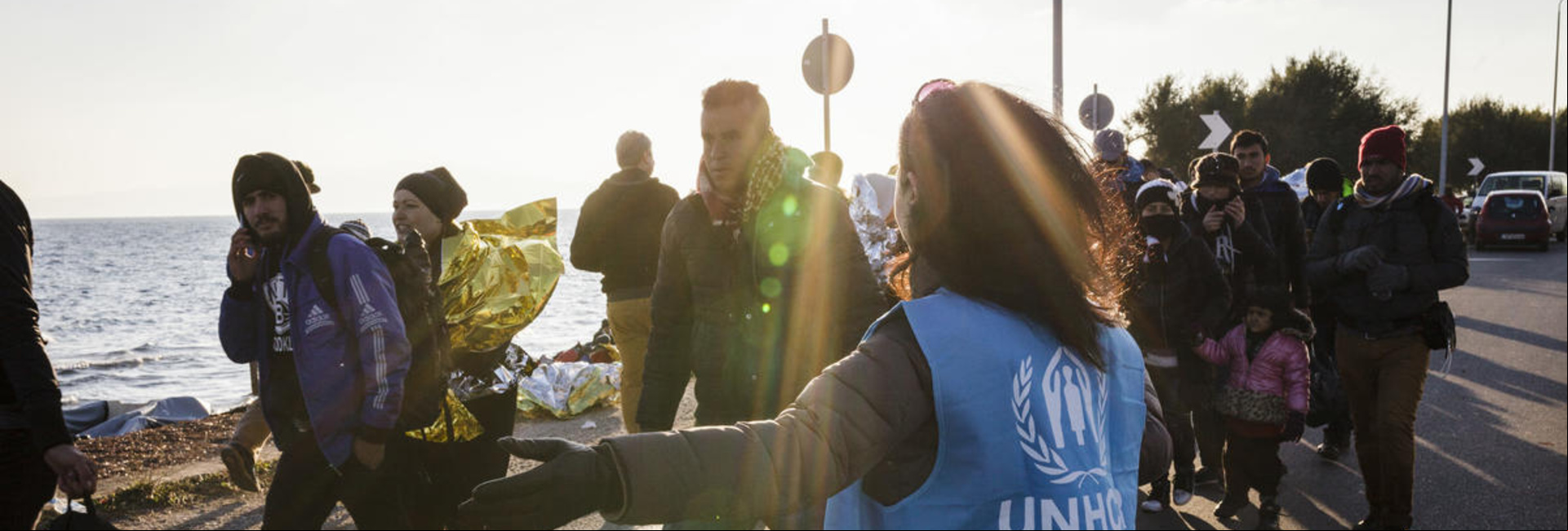 Una trabajadora de ACNUR dirige a un grupo de personas refugiadas de Siria e Irak para que puedan subir a un autobús. Una trabajadora de ACNUR dirige a un grupo de personas refugiadas de Siria e Irak para que puedan subir a un autobús.
