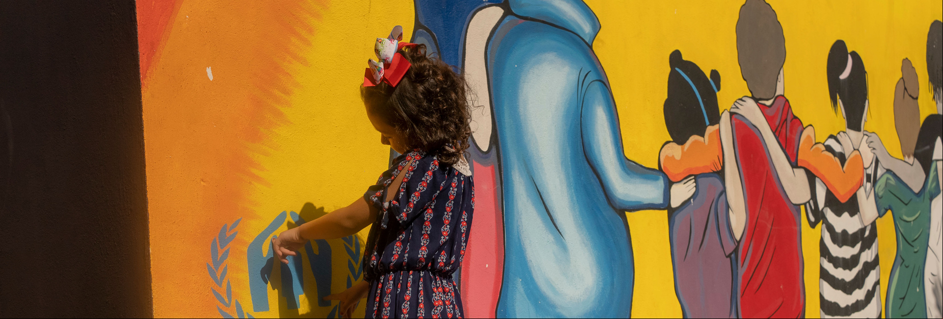 Una niña de espaldas hacia una pared de colores