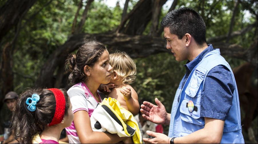 Una mujer con dos niños pequeños charla con un trabajador de ACNUR en Colombia. Una mujer con dos niños pequeños charla con un trabajador de ACNUR en Colombia.