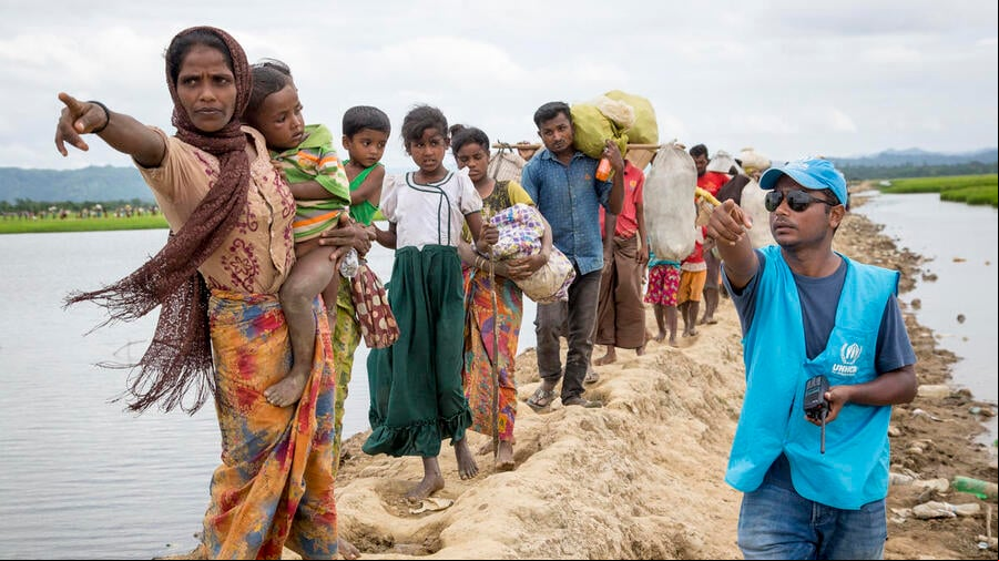 Rohingya arrivals at transit centre Una trabajadora de ACNUR le indica a un grupo de personas rohingyas refugiadas dónde se encuentra el centro de tránsito.