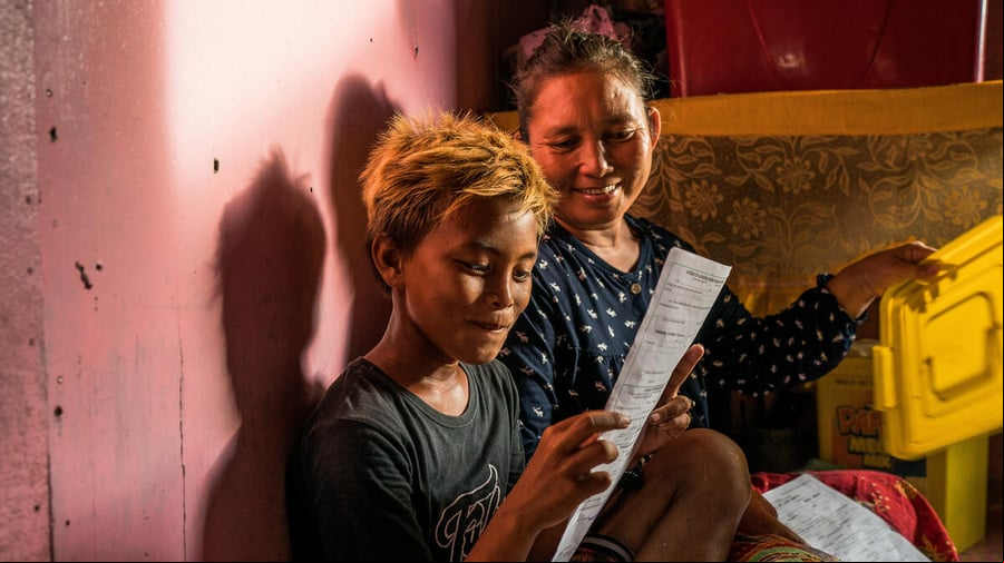 Un joven filipino sostiene alegremente su certificado de nacimiento; a lado suyo, una mujer que comparte su alegría por contar finalmente con un documento de identidad