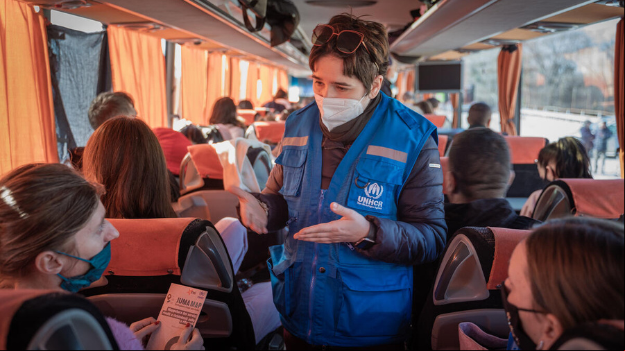 Un trabajador de ACNUR charla con personas refugiadas de Ucrania en un autobús