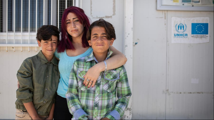 Una madre abraza a sus dos hijos; las tres personas miran fijamente a la cámara.
